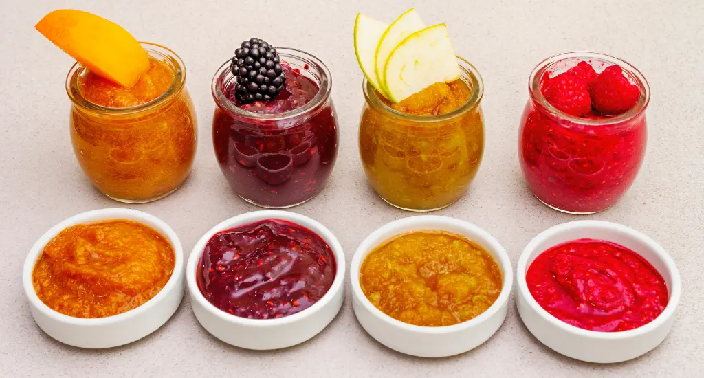 Colorful pureed foods in clear glass containers for pureed diet recipes, neatly arranged on a kitchen countertop.